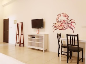 Een kamer met een televisie op een witte standaard, een houten ladder, een witte wandplank en een decoratief muurdecor.