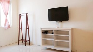 A room with a white TV stand, a flat-screen TV mounted above it, and a wooden ladder leaning against the wall. - Rainbow Homestay (Lyudao)