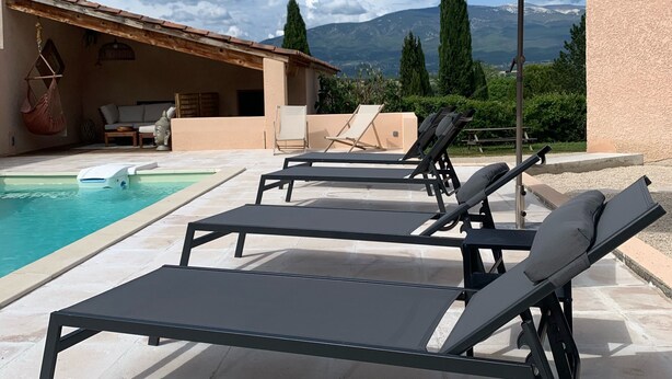 Zona piscina con lettini e ombrellone, una piscina e vista sulle montagne.