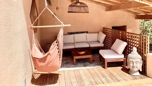 Un patio in legno con un'amaca, un divano e una statua di Buddha.