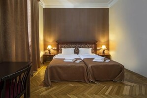 Una cama doble con cabecera de madera, dos mesitas de noche con lámparas y suelo de madera.