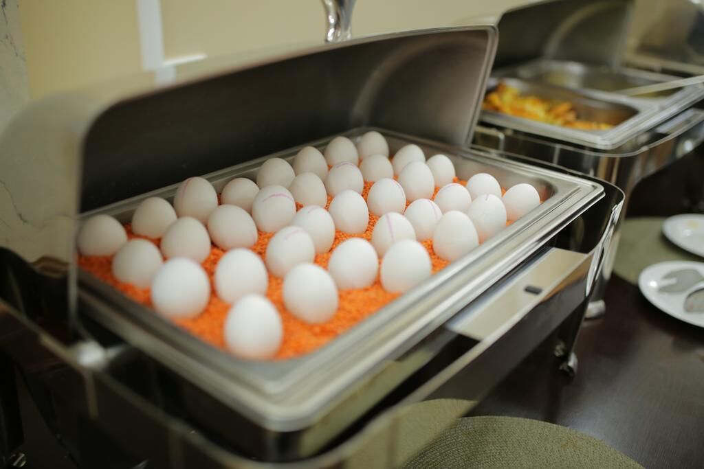 A buffet setup with a tray of white eggs on orange bedded trays.