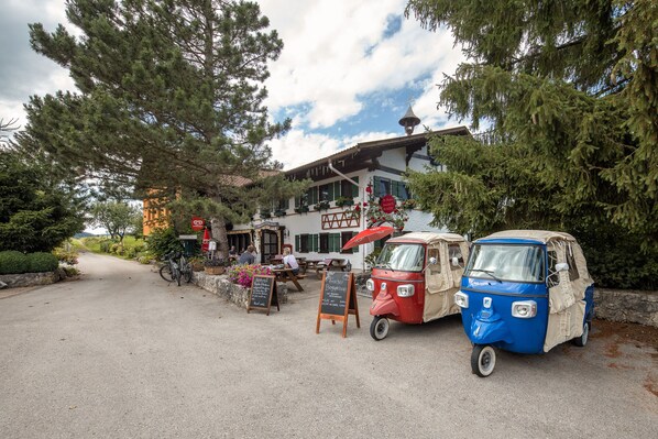 A rustic building with outdoor seating and a red and blue tuk-tuk parked in front. - Haus Magnushof (Eisenberg)