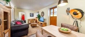 A cozy living room with a sofa, a coffee table, and a dining table with apples. - Haus Magnushof (Eisenberg)