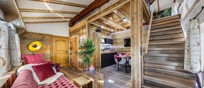 A cozy cabin interior with a wooden interior, a sofa, a dining area, and a small kitchen. - Haus Magnushof (Eisenberg)