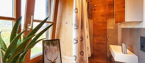 A bathroom with wooden cabinets, a shower curtain with heart patterns, and a sink. - Haus Magnushof (Eisenberg)