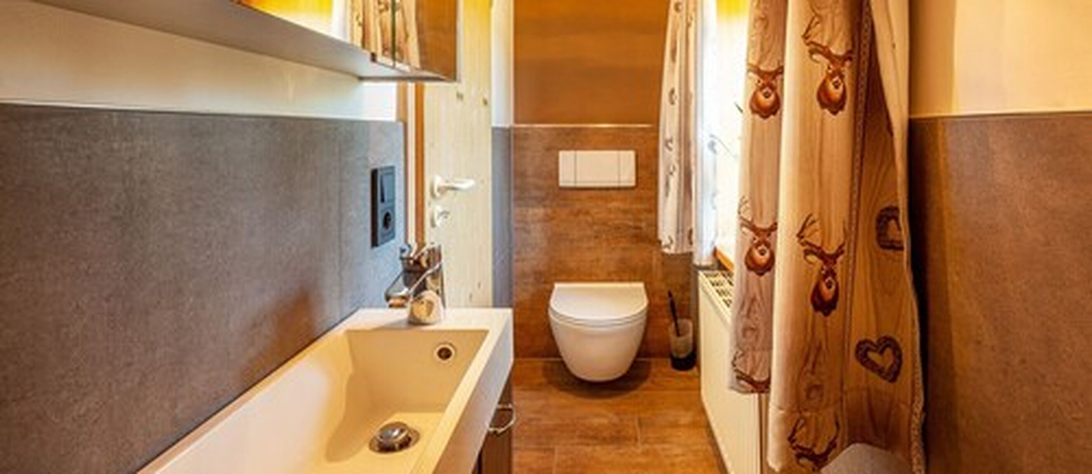 A bathroom with a bathtub, toilet, and shower curtain with animal prints.