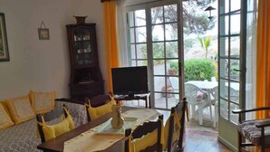 Un comedor con una mesa preparada para cuatro personas, un televisor y un armario.