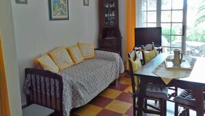 Una habitación con sofá, mesa de comedor, sillas, armario y ventana con cortinas.