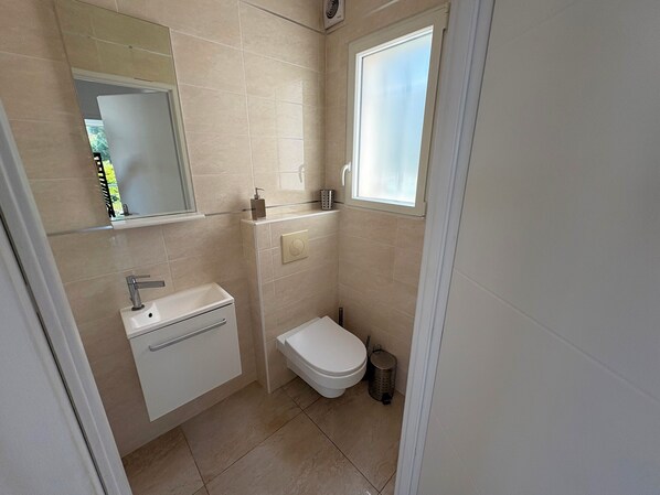 A small bathroom with a sink, toilet, and a window.