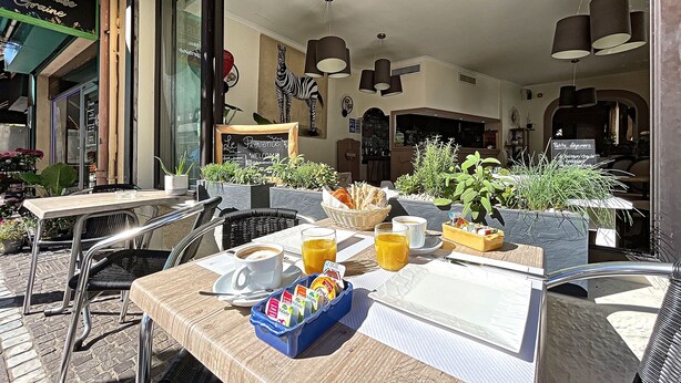 Un café en plein air avec des tables, des chaises et des plantes en pot.