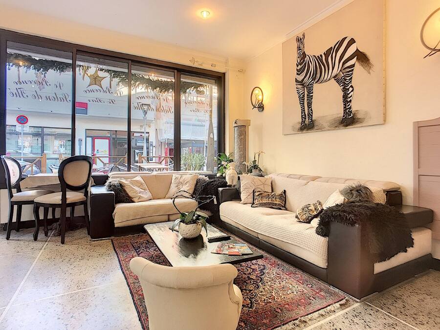 Un salón con sofá, sillas, una mesa de centro y un amplio ventanal con vista a la calle.