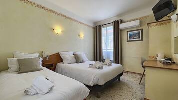 Une chambre d’hôtel avec deux lits, un bureau, une télévision et une fenêtre avec des rideaux.
