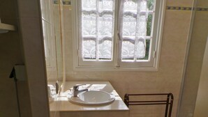 Een badkamer met toilet, wastafel en raam.