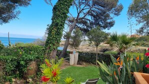 A garden with a view of the sea, a wooden deck, and a seating area. - La Calanque 263 villa (Les Issambres)