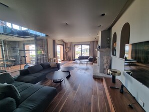 A spacious living room with a modern design, featuring a large sofa, a coffee table, and a fireplace.