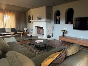 A modern living room with a fireplace, sofas, coffee tables, and a TV.