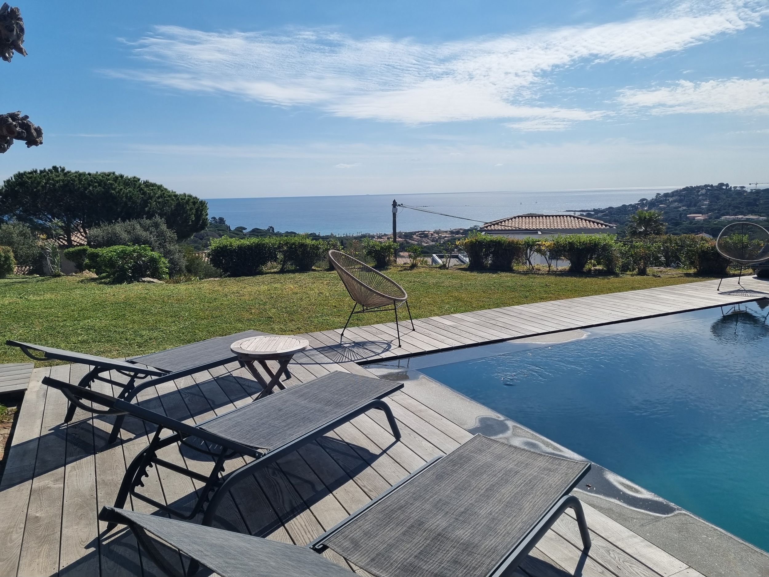 A poolside area with lounge chairs and a view of the sea.