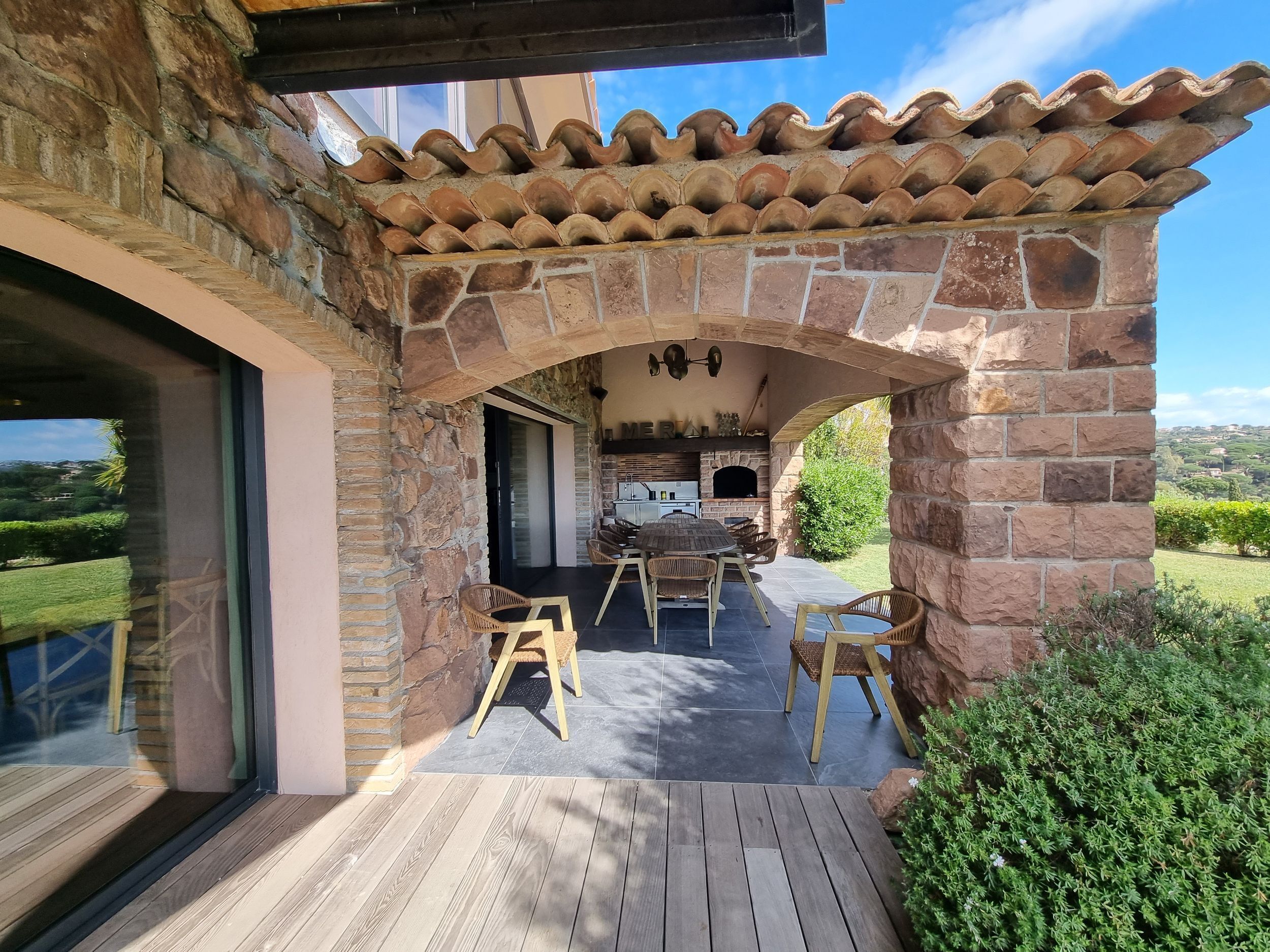 Un patio al aire libre con paredes de piedra, una chimenea de ladrillo y una terraza de madera.