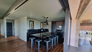 A modern kitchen with a central island, bar stools, and a built-in oven. - Pierre Jean 1823 villa (Sainte-Maxime)