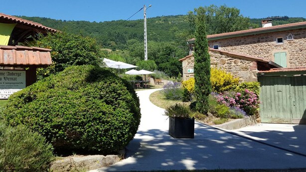 A rural village with stone buildings, a paved path, and lush greenery.
