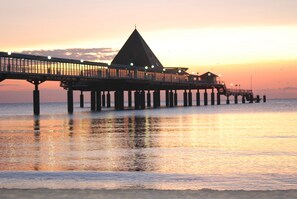 A pier extending into calm waters at sunset.
