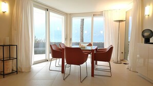 Un comedor con mesa y sillas, ventanas amplias y vistas al exterior.