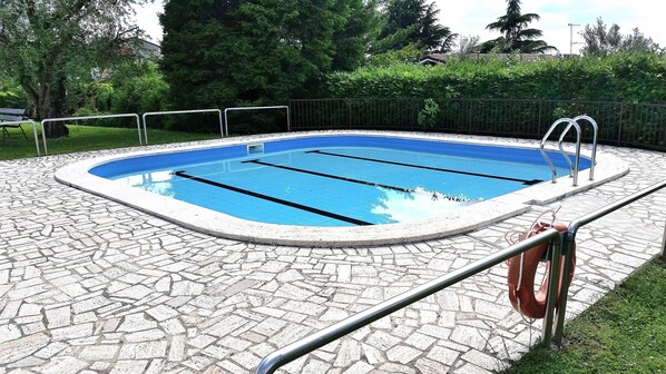 A rectangular swimming pool with a tiled edge, surrounded by a stone patio. - Villa Lisi With Pool (Bardolino)