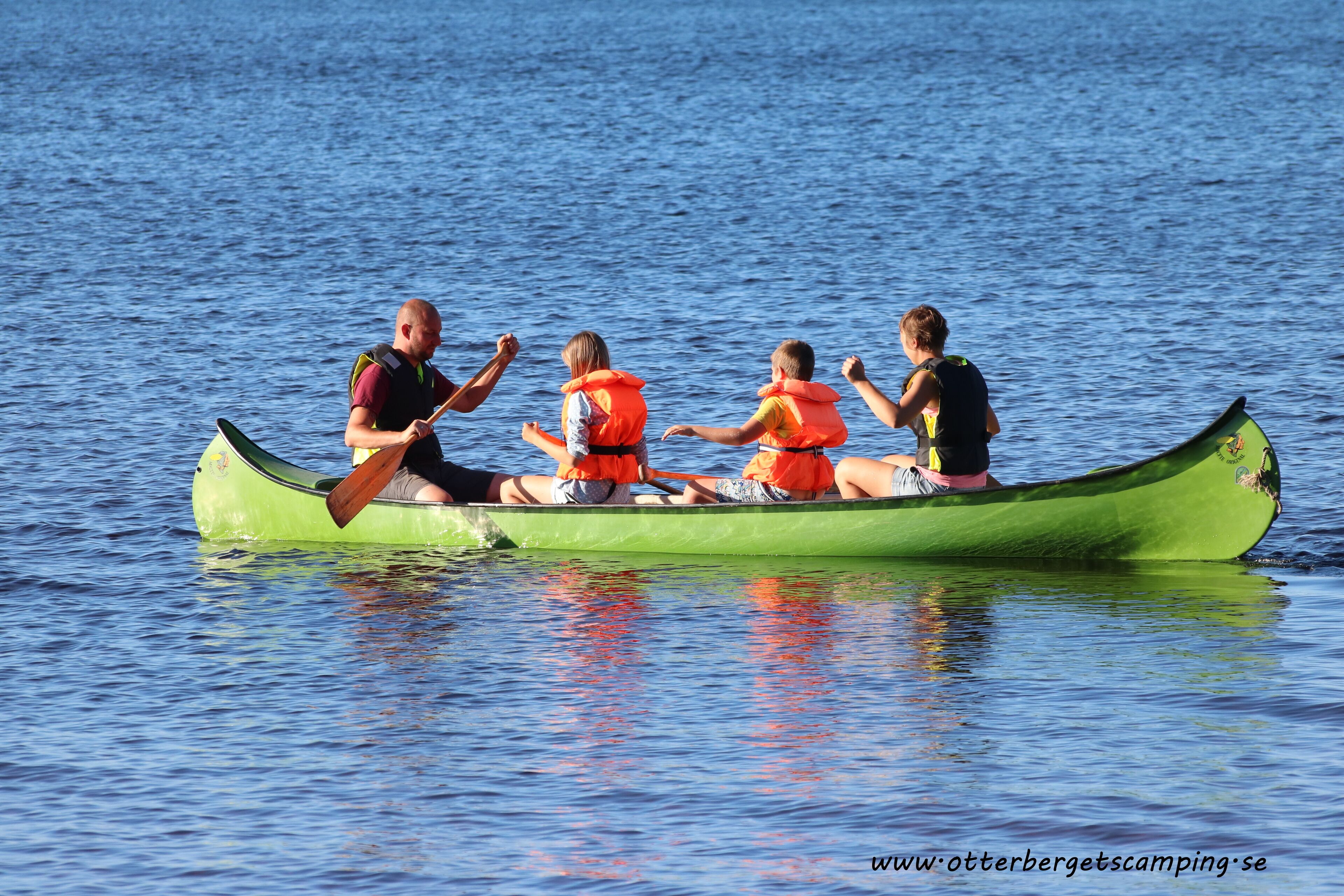 A group of people in a green canoe on a body of water.