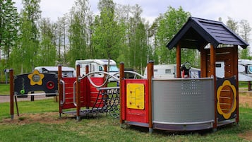 A playground with a climbing structure, a slide, and a small shelter.