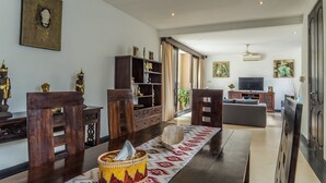A spacious living room with a large sofa, wooden furniture, a television, and decorative statues. - Villa Kiaja (Kerobokan)