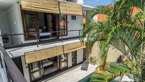A two-story building with a pool, large windows, and a balcony with a view of the pool. - Villa Kiaja (Kerobokan)