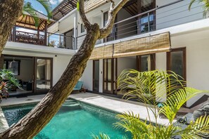 Una casa moderna con piscina, ventanas amplias y un balcón.