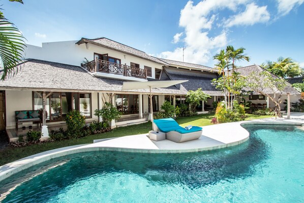 A modern house with a swimming pool, a covered patio, and a well-maintained garden.