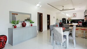 A modern living room with a dining area, a kitchen, and a hallway. - Villa Melati (Legian)