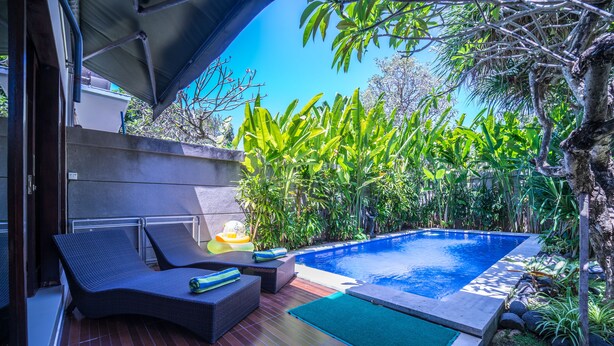 A poolside area with lounge chairs and a small pool. - Villa Cantik (Legian)