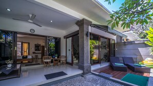 A modern outdoor living area with a stone mosaic floor, a ceiling fan, and a seating area with chairs and a table. - Villa Cantik (Legian)