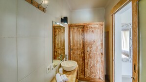 A bathroom with a wooden vanity, a large mirror, and a wooden door. - Villa Airin (Canggu)