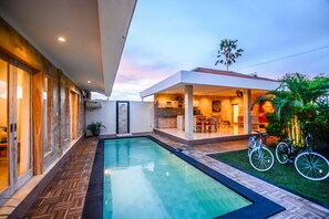 A modern house with a swimming pool, a covered patio, and bicycles. - Villa Airin (Canggu)