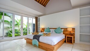 Une chambre moderne avec un grand lit, une table de chevet et une vue sur la verdure grâce à de grandes fenêtres.