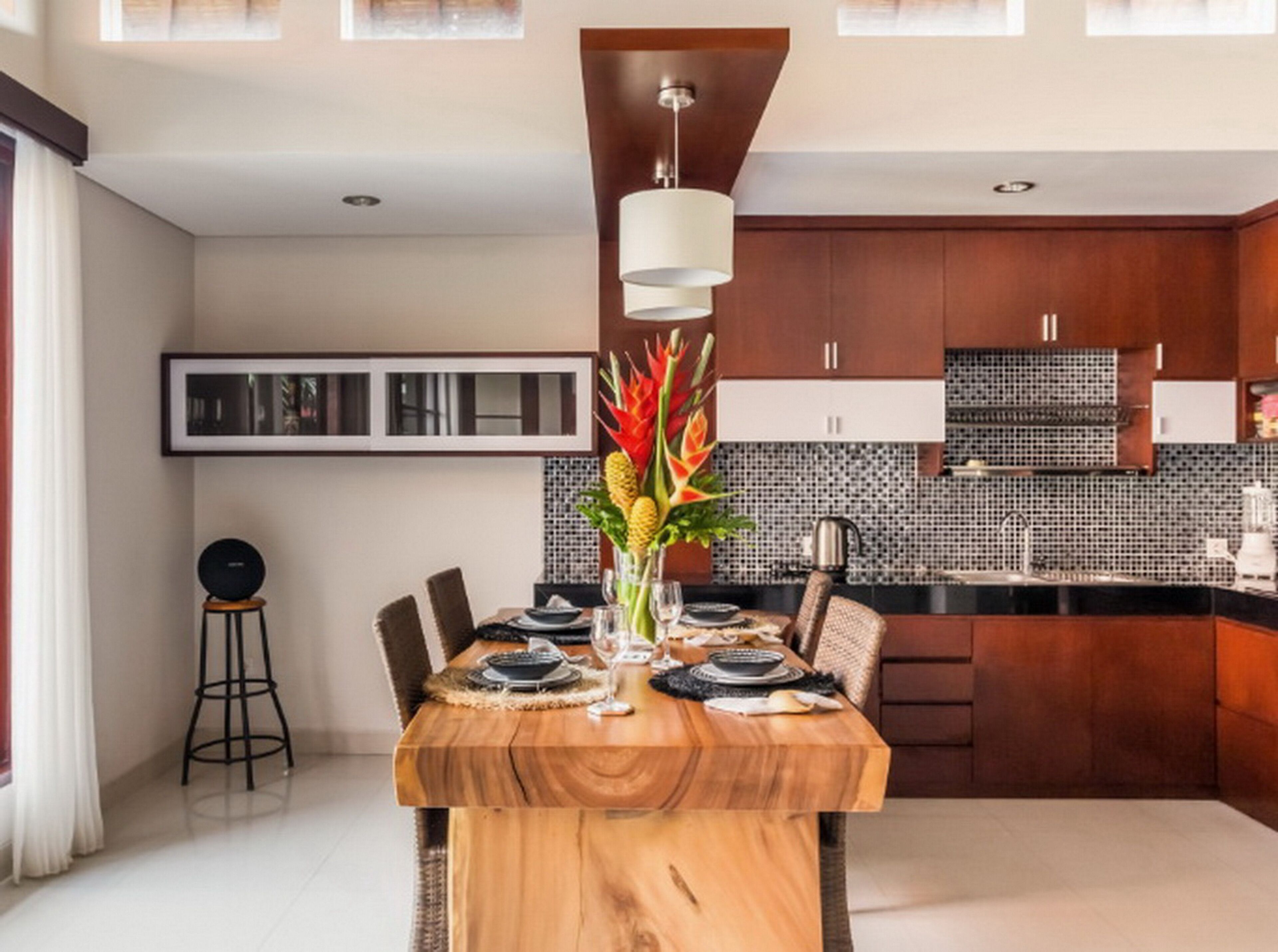 Una cocina moderna con armarios de madera oscura, salpicadero de azulejos y un comedor con mesa de madera para cuatro personas.