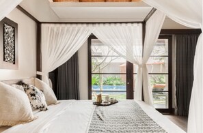 A bedroom with a large bed, a view of the outdoors, and a window with curtains.