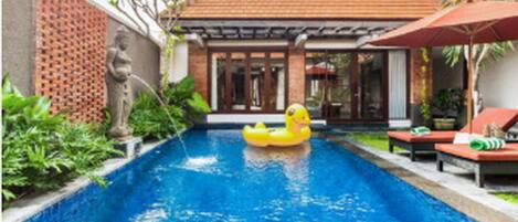 A swimming pool with a yellow inflatable duck, surrounded by lounge chairs and umbrellas.