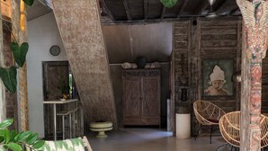 A room with a wooden ceiling, a green and white striped chair, a cabinet, and two wicker chairs. - Villa Wonderland (Seminyak)
