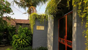 Un bâtiment à l’extérieur gris, avec une porte rouge et une enseigne indiquant « KELAPA VIEW 2 ».