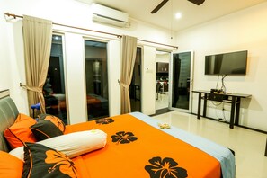 Una habitación de hotel con cama, cortinas, televisión y escritorio.