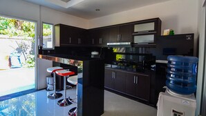 Une cuisine moderne avec des meubles de couleur sombre, un plan de travail noir et un distributeur d’eau.