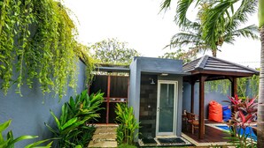 Une terrasse extérieure moderne, dotée d’une porte vitrée, d’une terrasse en bois et d’une végétation luxuriante.