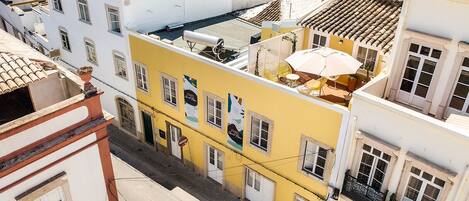Un bâtiment jaune, doté de nombreuses fenêtres et de balcons, entouré d’autres bâtiments.