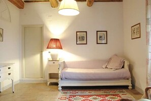 A bedroom with a bed, a nightstand, a lamp, and framed pictures on the wall.
